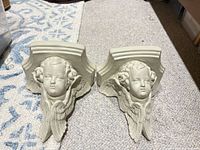 Pair of off-white plaster cherub corbels front view