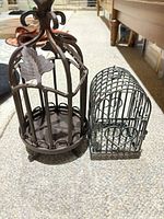 Two decorative metal birdcages side by side showing size difference and design details