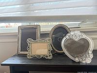 Four assorted ornate picture frames in silver-tone, gold-tone and clear resin