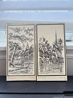 Both signed European village prints side by side showing artwork, signatures and titles