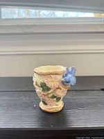 Front view of porcelain floral egg cup with blue bird accent