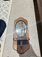 Front view showing oval mirror, wood frame and shelf