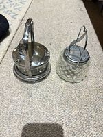 Both glass servers side by side showing silver-plated lids and handles