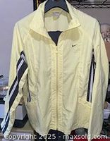 Full front view of pale yellow Nike track jacket with sleeve stripes and zip pockets