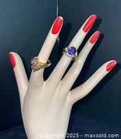 Both gold-tone rings displayed on hand form