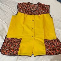 Front view of yellow snap-front apron smock showing floral yoke, pockets and snaps