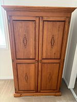 Front view of closed cabinet showing carved panels and knobs