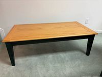 Full view of coffee table showing natural wood top and black legs