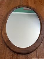 Front view of oval mirror showing wood frame and reflective surface