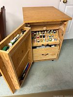 Cabinet open showing interior thread racks, spools, drawer and notions