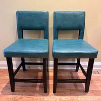 Front view of both stools showing seat, legs, and upholstery color