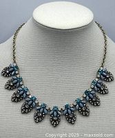 Front view showing rhinestone leaf drops and blue/green stones