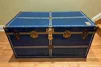 Front and top view of blue metal trunk showing hardware and overall condition
