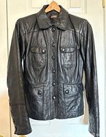 Front view of black leather jacket on hanger