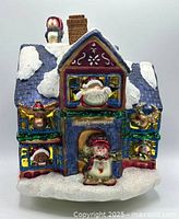 Front view of hand-painted glass Santa’s Workshop house showing characters and snow detail