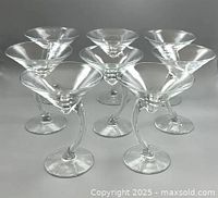 Set of eight clear martini glasses with curved stems, angled front view