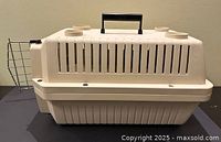 Side view of beige plastic carrier showing handle, ventilation slots, door removed