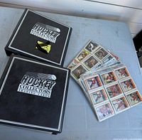 Two binders labelled Hockey Collectors Trading Cards and stack of sleeved cards on table