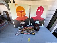 Front view of all items including two canvas prints, Monopoly game, cap, stickers, pin