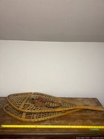 Full view of both snowshoes on table with measuring tape showing length