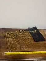 Full set of twelve brass clamps laid out with pouch and tape for scale