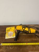 Full view of grinder, handle, cord, sanding disc pack and measuring tape for scale