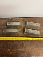 Four nickel ingots with measuring tape showing length about 11 cm