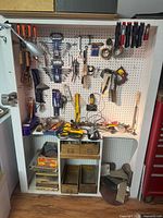 Overall pegboard station showing majority of hand tools, drill, charger, sandpaper and accessories