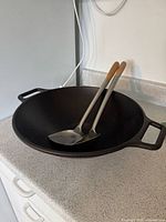 Top view of cast iron wok with utensils inside