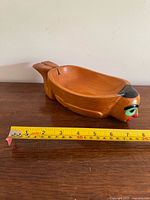 Side view of carved wooden swimmer bowl with measuring tape showing length