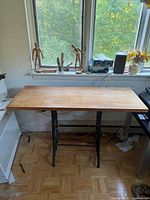 Full view of table against window showing wood top and entire base