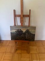 Full view of wooden tabletop easel holding landscape oil painting