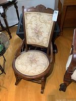 Front view of wooden rocking chair showing upholstery and carving