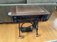 Full front view of Raymond treadle sewing machine cabinet with cast iron base and oak block feet visible