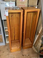 Front view of both wood bookshelf cabinets standing upright with bag of shelf clips on top