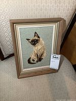 Full view of framed Siamese cat needlepoint on chair