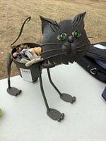 Front three-quarter view of metal cat planter with toys visible in pot