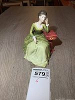 Front view of Royal Doulton Carolyn figurine on table with lot number
