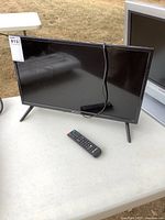 Front view of Sansui 24-inch TV on stand with remote placed in front