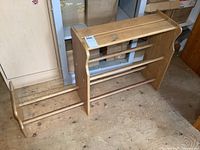 Full view of solid wood shoe rack laid on floor, showing side panels and dowel shelves