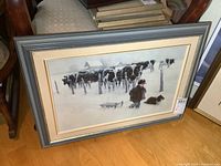 Full view of framed signed print leaning against chair
