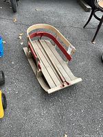 Side view of wooden sleigh showing red rails and runners