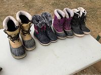 Four pairs of winter boots lined on table