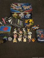 Group shot showing all items: tins, pins, figures, cards, coins