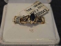 Ring close-up showing 10k gold stamp tag, stones, band design