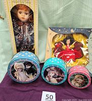 Group photo showing both boxed dolls and three nesting tins