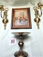 Lot overview showing framed painting, two wall sconces, pedestal candle holder