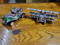 Budweiser biplane and Cristal car models side by side on wooden surface