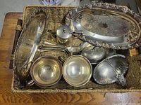 Basket containing assorted silver-plated platters, cups, teapot, gravy boat, covered dish and utensils