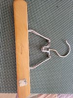 Full view wooden clamp hanger showing metal hardware and partial label